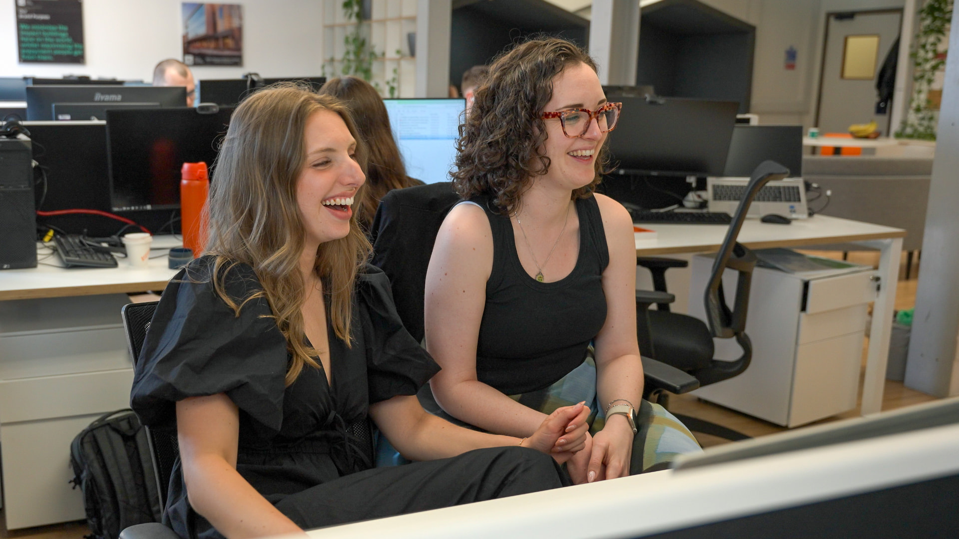 Two CPW colleagues laughing together at their desks